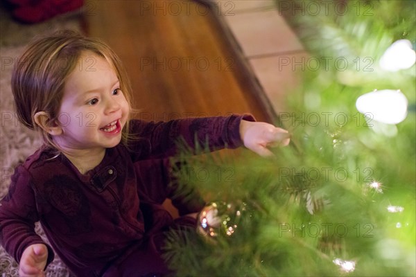 Caucasian girl pointing at ornament on Christmas tree
