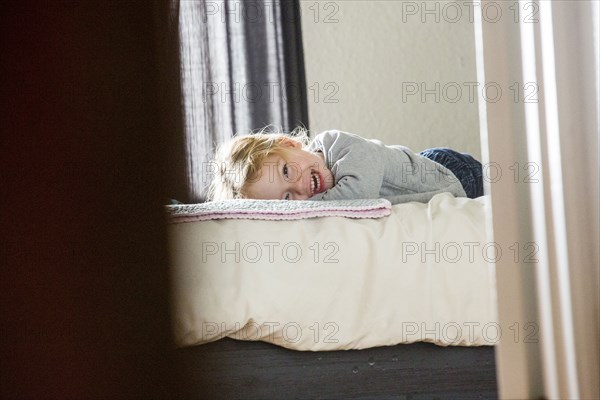 Caucasian girl laying on bed beyond doorway