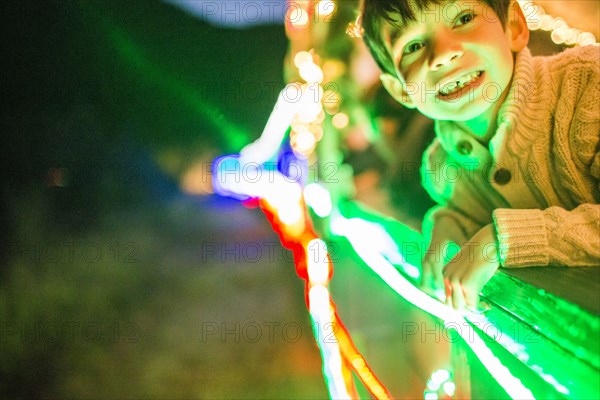 Neon lights glowing on face of Mixed Race boy