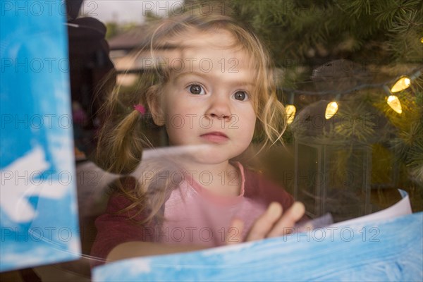 Serious Caucasian girl leaning on window