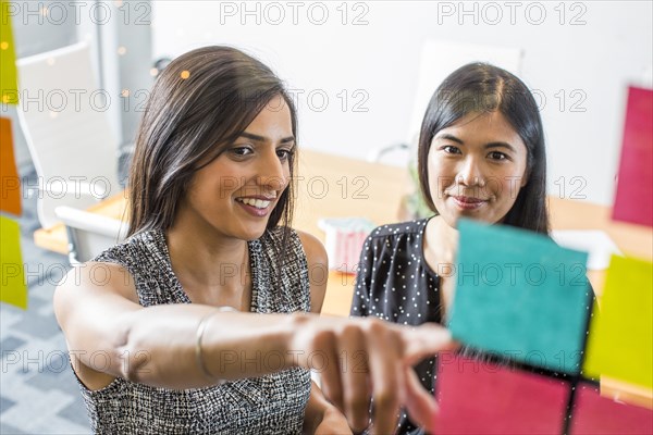 Women reading adhesive notes in office