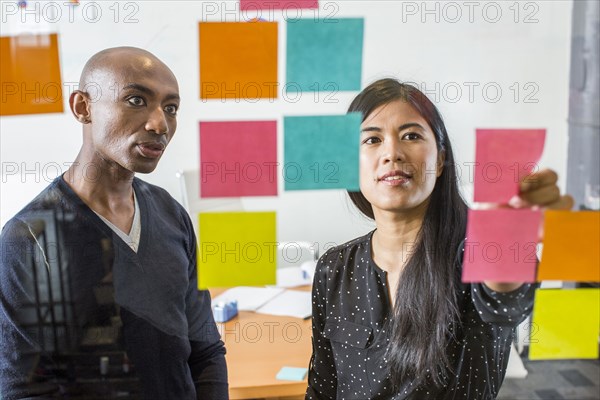 Woman and man reading adhesive notes in office