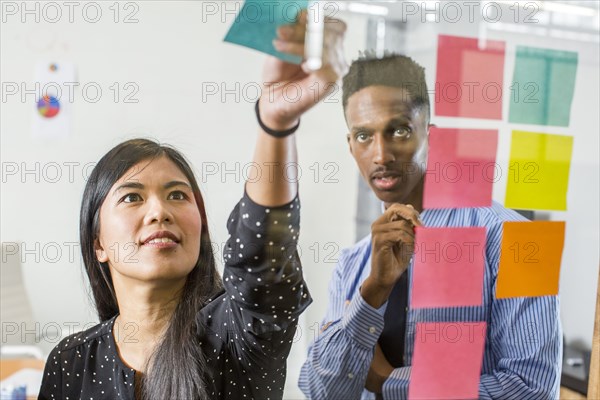 Woman and man reading adhesive notes in office