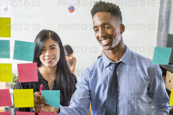 Woman and man reading adhesive notes in office