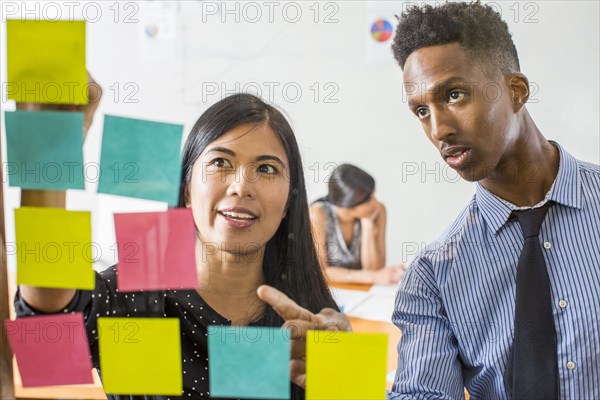 Woman and man reading adhesive notes in office