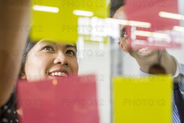 Woman and man reading adhesive notes in office