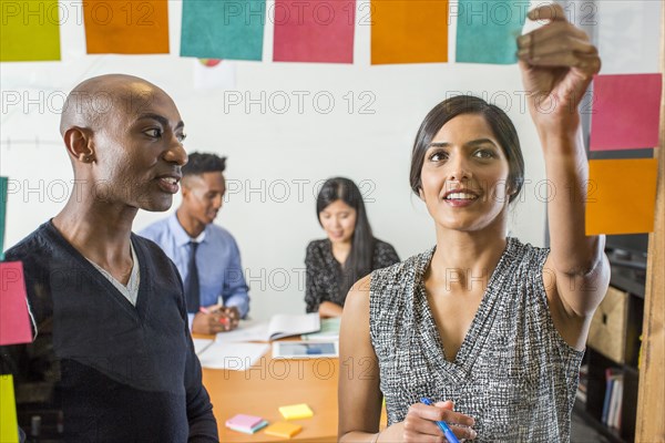 Woman and man reading adhesive notes in office