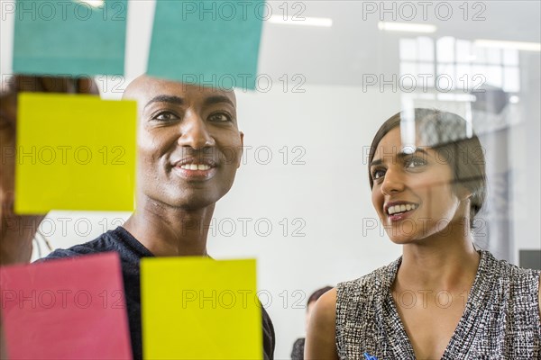 Woman and man reading adhesive notes in office