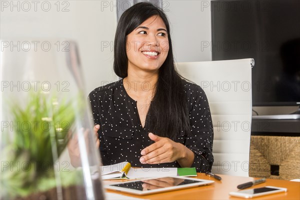 Smiling Asian woman gesturing in meeting