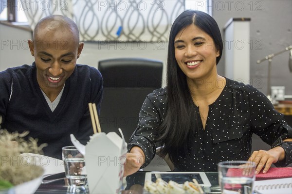 Woman reaching for carton of food in meeting