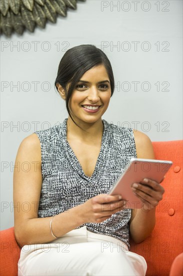 Smiling Asian woman holding digital tablet