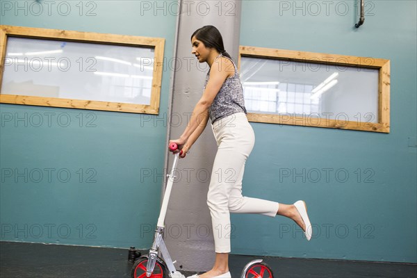 Asian woman riding scooter indoors