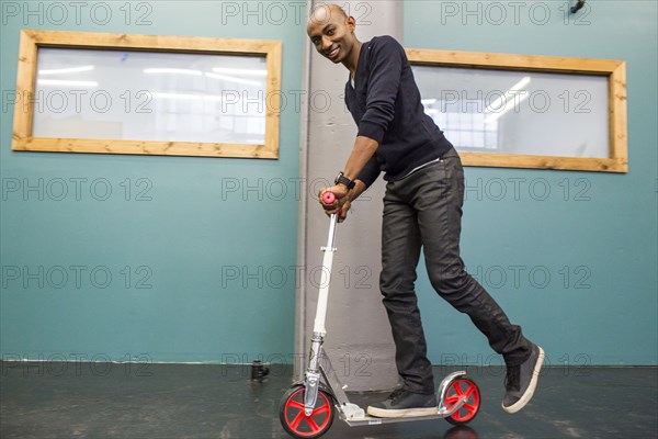 African American man riding scooter indoors