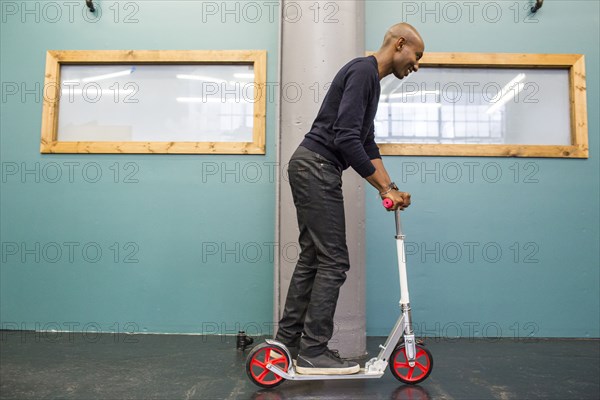 African American man riding scooter indoors