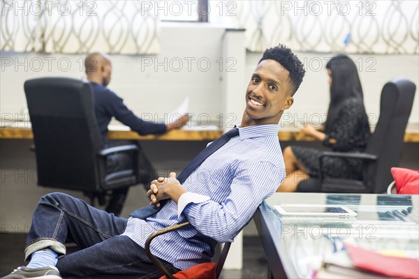 Portrait of smiling Black man relaxing in office