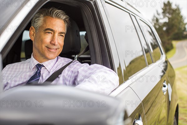 Smiling Caucasian businessman driving car