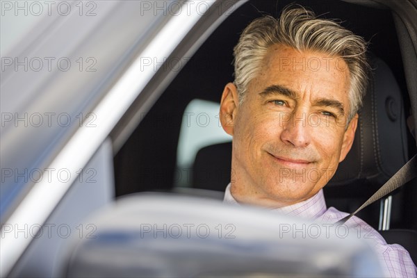 Smiling Caucasian businessman driving car