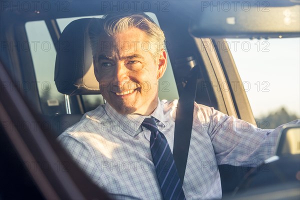 Smiling Caucasian businessman driving car