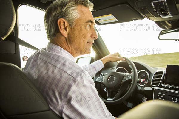 Smiling Caucasian businessman driving car