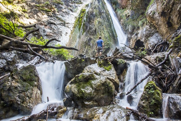 Caucasian man standing on rocks watching waterfall