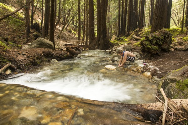 Caucasian man washing foot in forest river