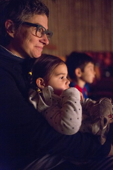 Mixed Race mother holding daughter in lap at movie theater