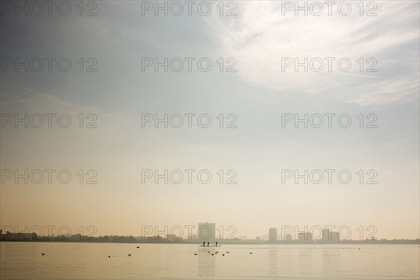 Distant people paddleboarding in river