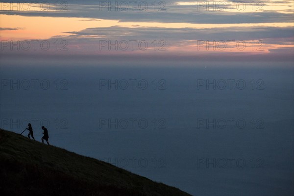 Hikers climbing hill at sunset