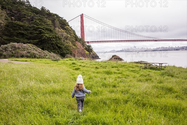Caucasian girl walking in grass near bridge