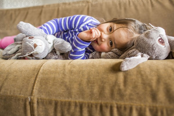 Caucasian girl laying on sofa sucking thumb