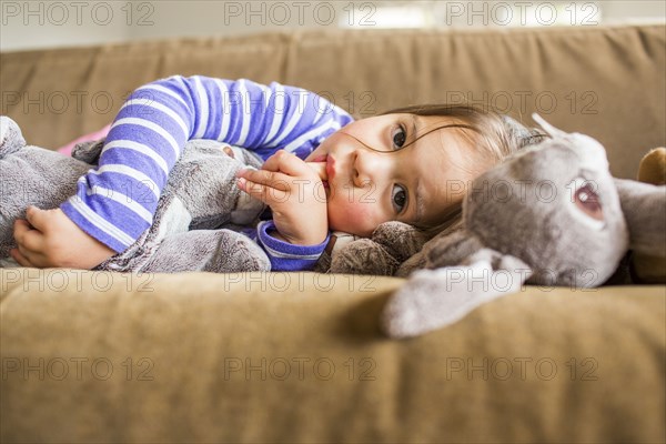 Caucasian girl laying on sofa sucking thumb