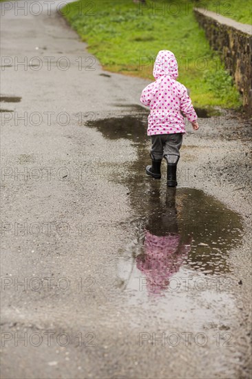 Caucasian girl wearing boots walking in puddle