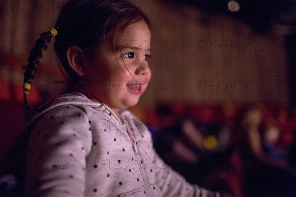 Mixed Race girl watching movie in theater