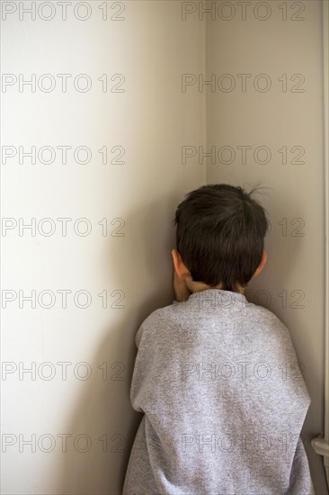 Mixed Race boy standing in corner