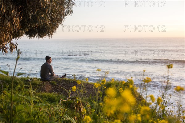 Caucasian man admiring scenic view of ocean at sunset