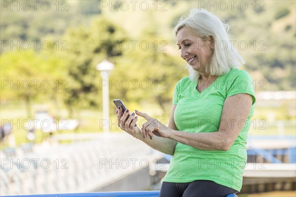 Older Caucasian woman texting on cell phone outdoors