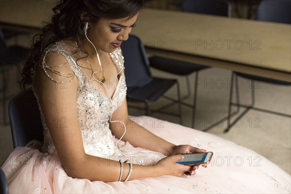 Smiling Hispanic girl listening to cell phone with earbuds