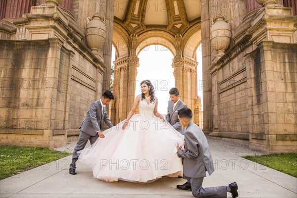 Hispanic boys holding skirt of girl