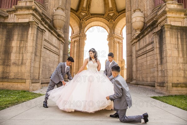 Hispanic boys holding skirt of girl