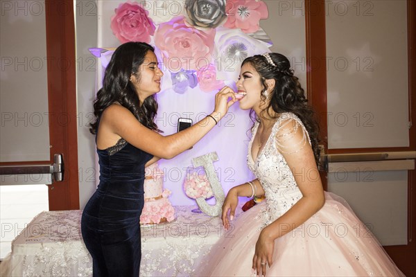 Hispanic girl feeding cookie to friend