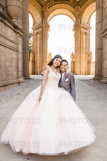 Hispanic girl wearing gown hugging boy