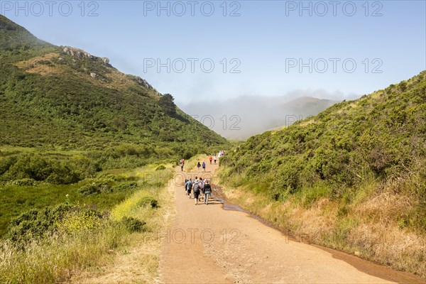 People walking on dirt road in valley