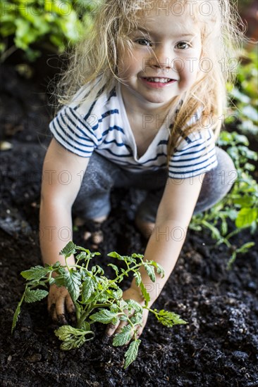 Caucasian girl posing with plant in garden