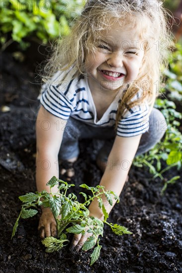 Caucasian girl posing with plant in garden