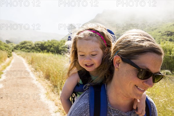 Caucasian mother carrying daughter while hiking