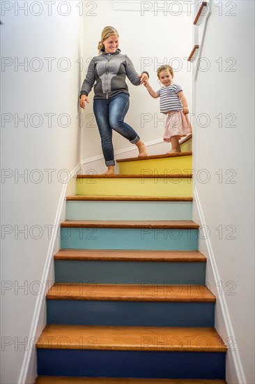 Caucasian mother and daughter descending multicolor staircase