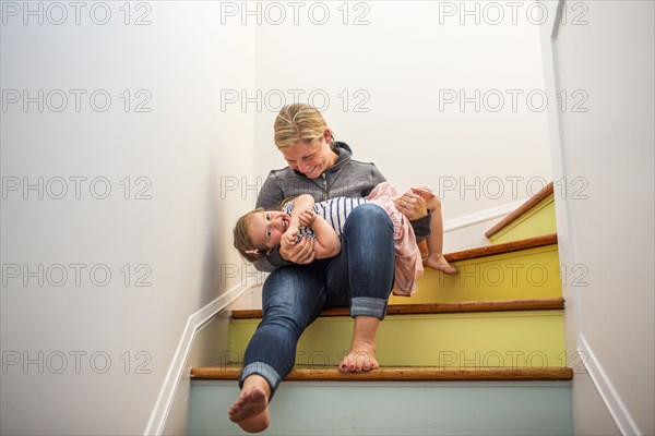 Caucasian mother and daughter playing on multicolor staircase