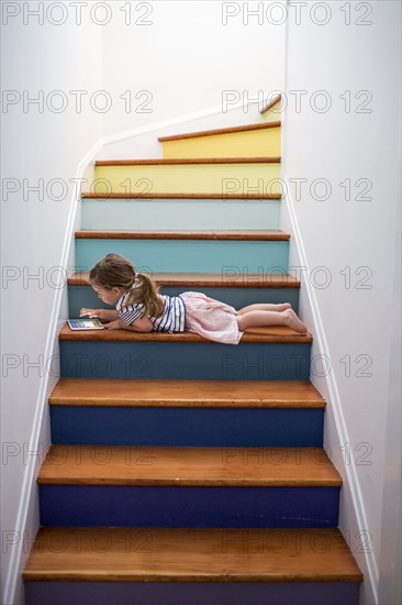 Caucasian girl using digital tablet on multicolor staircase