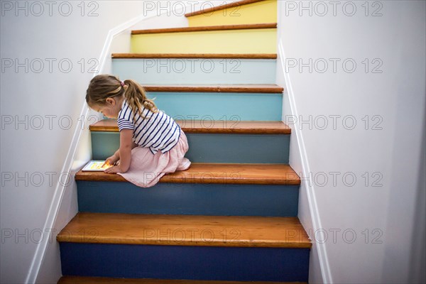 Caucasian girl using digital tablet on multicolor staircase