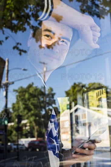 Smiling Chinese man leaning on window holding cell phone